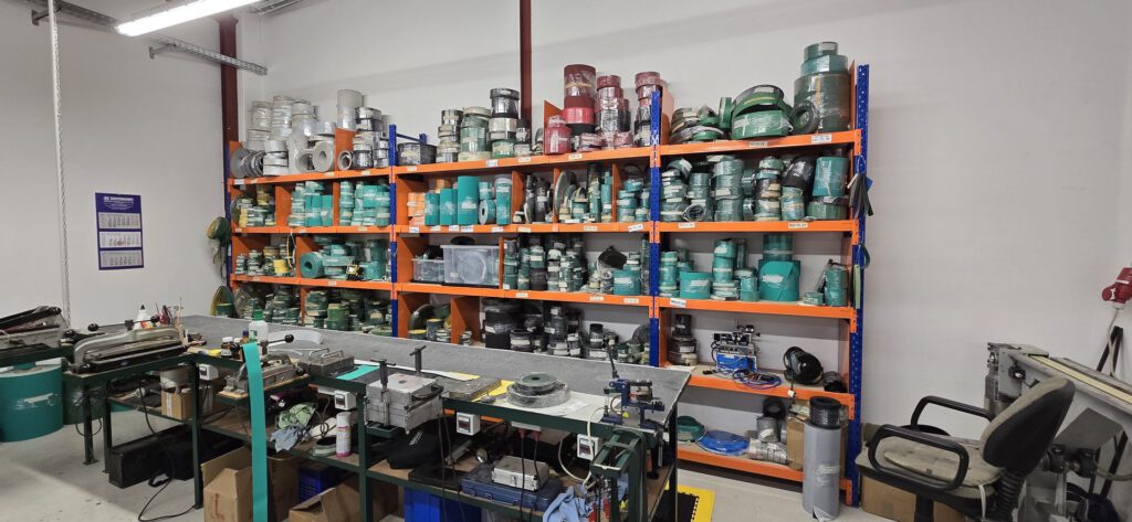 Materialregal mit Band- und Riemenrollen in der Produktionshalle von STA-Simon